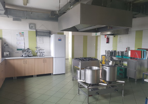 Widok kuchni przedszkolnej. Na środku pomieszczenia duże garnki