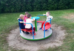 Dzieci bawią się na karuzeli na przedszkolnym placu zabaw