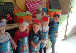 Dzieci stoją z opaską na głowie z emblematem jabłka.