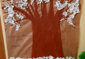 Drzewo namalowane na szarym papierze, ozdobione bibułą i watą