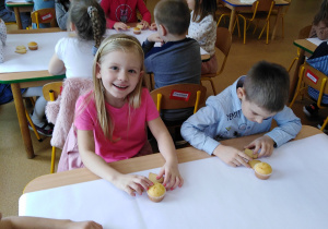 Dzieci siedzą przy stolikach, w oczekiwaniu na dekorowanie ciasteczek