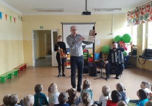 Pan Maciej czyta dzieciom książeczkę o instrumentach w orkiestrze