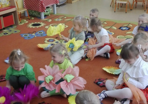 po zakończonym tańcu dzieci z kwiatami siedzą na dywanie