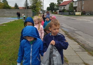 Dzieci idą z workami sprzątać śmieci w okolicy przedszkola