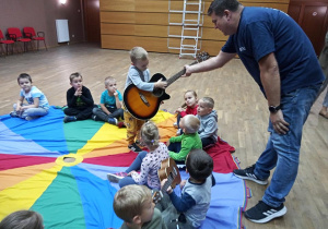 Dzieci biorą udział w zajęciach muzycznych - Kacper próbuje grać na gitarze