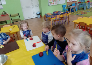 Dzieci przy stoliku kroją owoce