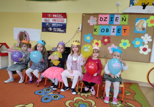 Dziewczynki siedzą na krzesełkach, trzymają balony