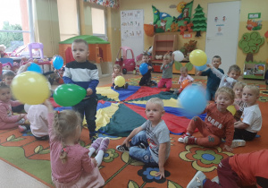 Dzieci podczas zabawy z chusta animacyjna i balonami