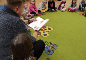 Dzieci siedzą na dywanie i słuchają opowieści
