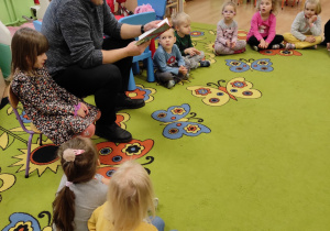 Dzieci siedzą na dywanie i słuchają opowieści