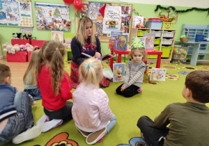 Dzieci słuchają opowieści czytanej przez panią bibliotekarkę