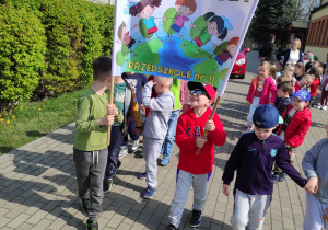 Dzieci z transparentem przed przedszkolem przygotowują się do happeningu