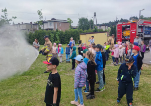 Dzieci podziwiające wodę laną przezpana strażaka z węża strażackiego