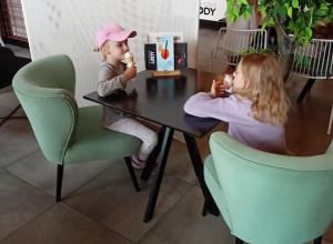 Dziewczynki siedzą przy stoliku i jedzą lody