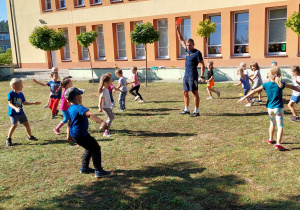 Dzieci z trenerem podczas rozgrywek sportowych w ogrodzie przedszkolnym