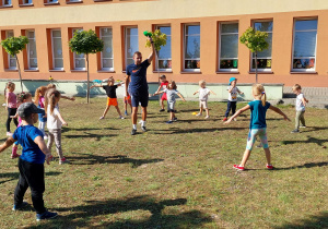 Dzieci z trenerem podczas rozgrywek sportowych w ogrodzie przedszkolnym