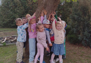 dzieci przytulają się do drzewa