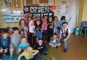 Dziewczynki z tulipanem w ręku pozują na tle dekoracji Dzień Kobiet