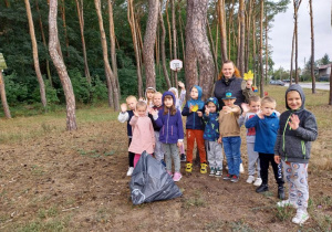 Dzieci pozują do zdjęcia w lesie podczas sprzątania