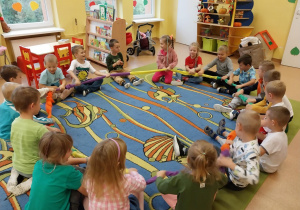 Dzieci bawią się w kole na dywanie