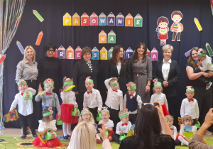 Dzieci stoją na tle dekoracji i pozują do zdjęcia grupowego