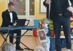 dzieci słuchają utworu, chłopiec prezentuje portret kompozytora