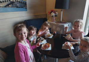 Dzieci siedzą przy stoliku z deserkami
