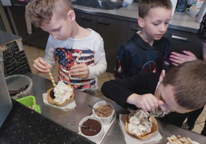 Chłopcy stoją przy blacie cukierniczym