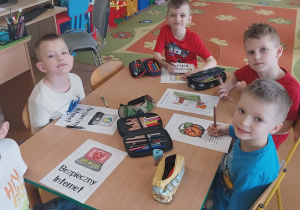 Chłopcy siedzą przy stoiku i kolorują obrazki o Internecie