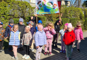 Dzieci pozują z transparentem z napisem Mali ekolodzy