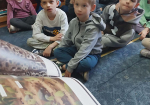 dzieci słuchają bajki czytanej przez nauczyciela w bibliotece