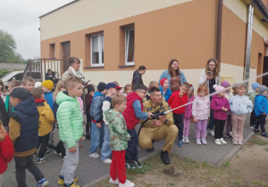 dzieci wraz ze strażakiem polewają wodą ogród z węża gaśniczego