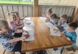 Dzieci pod altanką degustują pizzę