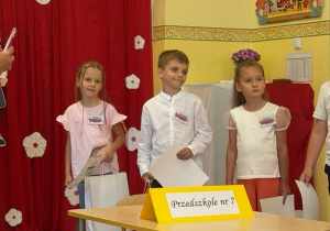 chłopiec stoi przy stoliku
