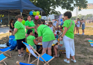 Grupka osób obserwująca jak dzieci malują kamienie