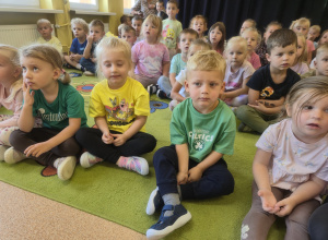 Dzieci siedzą na dywanie podczas koncertu