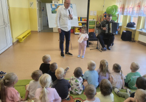 Dzieci siedzą na dywanie podczas koncertu