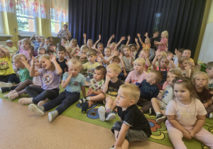 Dzieci siedzą na dywanie podczas koncertu