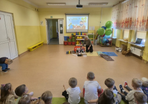 Dzieci podczas warsztatów siedzą na dywanie