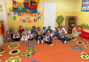 Dzieci z wychowawczynią siedzą na dywanie