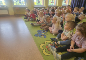 Dzieci siedzą na dywanie podczas koncertu