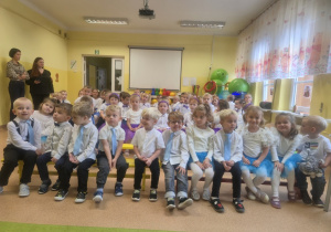 Dzieci siedzą na ławeczkach